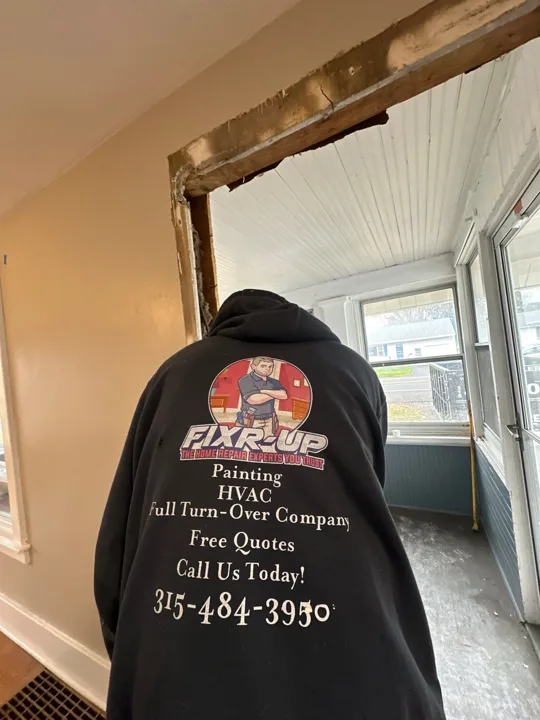 A Fixr-Up team member works at an exposed doorway opening as the surrounding trim and wall surfaces are prepared for the next stage.