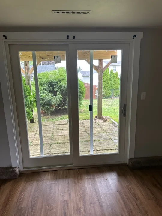A white sliding glass patio door with matching interior casing brings daylight into the room and opens onto the patio.